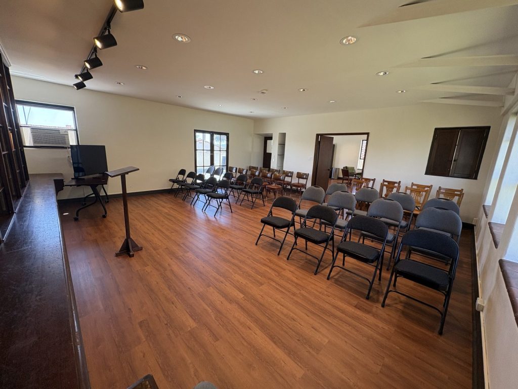 The library arranged for a lecture, with a lectern and screen facing rows of chairs.