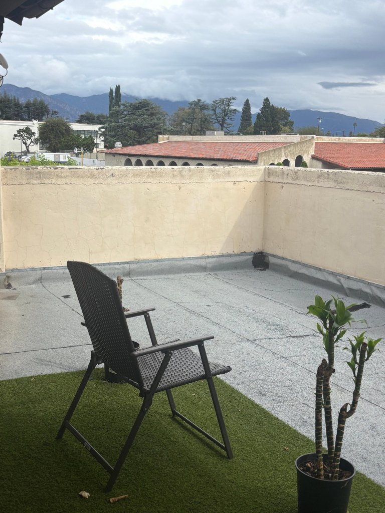 A chair on the Center's roof terrace, looking out over red tile roofs and trees toward the San Gabriel Mountains.
